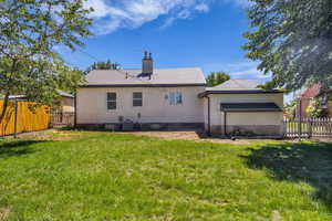 Rear view of house with a fenced backyard, brick siding, and a chimney