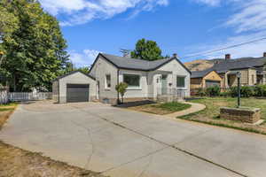 View of front of house featuring driveway, a garage, and an outbuilding