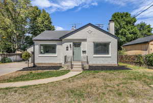 Bungalow featuring a chimney and brick siding