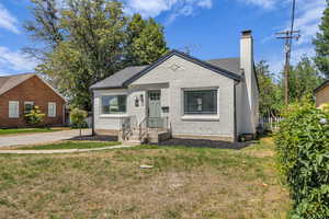 Bungalow-style home featuring a chimney, a front yard, and brick siding