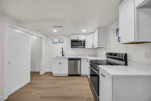 Kitchen featuring stainless steel appliances, white cabinetry, light wood-style floors, and recessed lighting