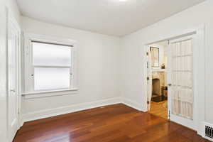 Unfurnished room featuring baseboards and dark wood-style flooring