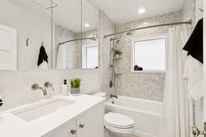Bathroom featuring shower / bath combo with shower curtain, decorative backsplash, and vanity