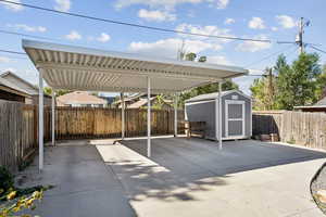 Fenced backyard with a storage unit and a detached carport