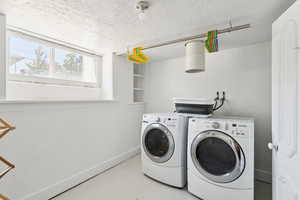 Laundry area with separate washer and dryer and a textured ceiling