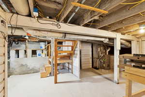 Unfinished basement featuring stairs and heating unit