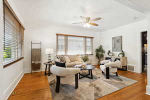 Living area with wood finished floors, a ceiling fan, and a textured ceiling