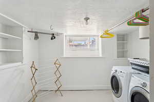 Laundry area with washer and clothes dryer and a textured ceiling