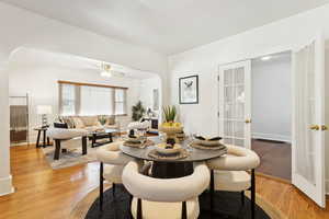 Dining room with arched walkways, light wood-type flooring, and ceiling fan