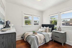 Bedroom with multiple windows and dark wood-type flooring