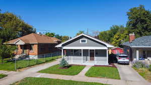 Bungalow-style home with a porch, driveway, a front yard, and brick siding
