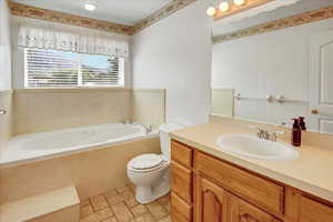 Full bath featuring a jetted tub, vanity, and light tile patterned floors