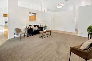 Living room with light carpet, a ceiling fan, high vaulted ceiling, and light tile patterned floors