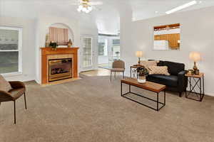 Living room with ceiling fan, light colored carpet, and a tiled fireplace