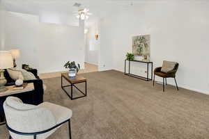 Living area with ceiling fan and light carpet