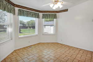 Dining area with bay bump out, tile floors and ceiling fan.