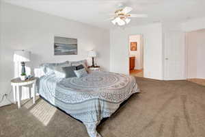Bedroom with light colored carpet, connected bathroom, and a ceiling fan