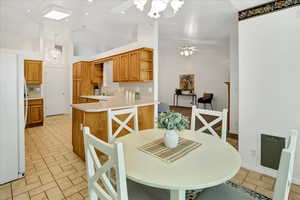 Dining space featuring a ceiling fan, a chandelier, and high vaulted ceiling