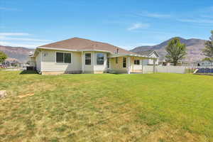 Rear view of property featuring a mountain view, a patio area, and a shingled roof