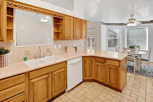 Kitchen with ceiling fan, light countertops, backsplash, and dishwasher