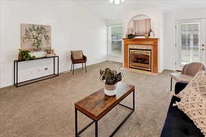 Living area featuring light colored carpet, a tile fireplace, and vaulted ceiling