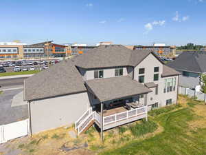 Back of property featuring roof with shingles, stucco siding, and covered deck