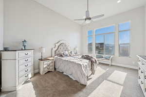 Main level primary bedroom with light carpet, ceiling fan, and recessed lighting