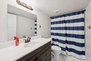 Full bath with a textured ceiling, vanity, and curtained shower