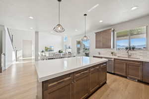 Kitchen featuring tasteful backsplash, decorative light fixtures, light LVP flooring, dishwasher, and recessed lighting