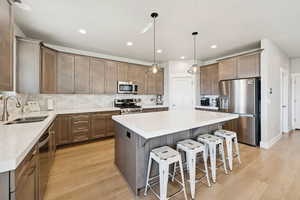 Kitchen with appliances with stainless steel finishes, a breakfast bar area, a center island, tasteful backsplash, and hanging light fixtures