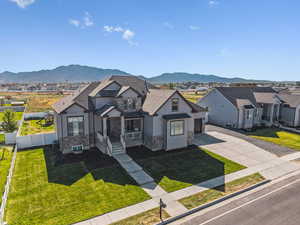View of front facade featuring stone siding, driveway, a mountain view, a garage, and a residential view