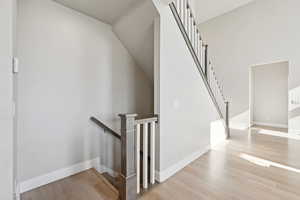 Stairs with wood finished floors and baseboards
