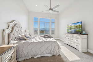 Main level primary suite featuring light colored carpet and a ceiling fan