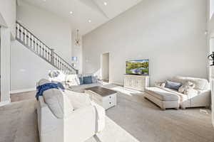 Living area with stairway, a towering ceiling, carpet floors, recessed lighting, and a chandelier