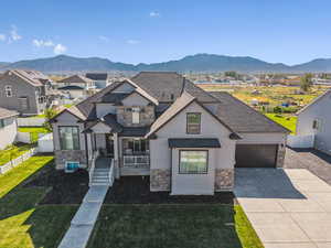 View of front facade with stone siding, driveway, an attached garage, and a mountain view