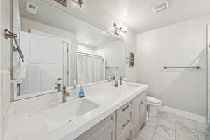 Full bathroom featuring light marble finish floors, double vanity, and a shower with shower curtain