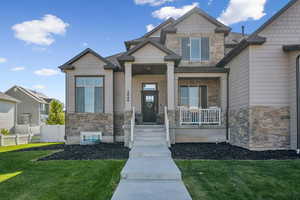 Entrance to property with stone siding, a yard, and covered porch