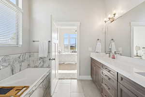 Ensuite bathroom with plenty of natural light, double vanity, a bath, and light tile patterned floors