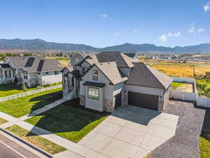 View of front facade featuring driveway, stone siding, a garage, a mountain view, and a residential view