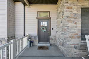 Entrance to property featuring stone siding and covered porch