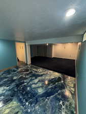 Empty room with a textured ceiling and baseboards