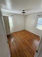 Spare room featuring wood-type flooring and baseboards