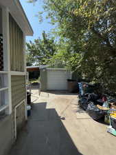View of patio with driveway, an outbuilding, and a detached garage