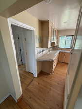Kitchen with tile countertops, light brown cabinetry, light wood finished floors, and decorative backsplash