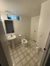 Bathroom with a textured ceiling and light floors