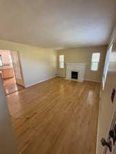 Unfurnished living room featuring light wood-type flooring and a fireplace with flush hearth