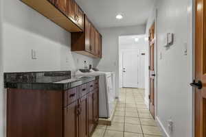 Laundry room featuring cabinet space, light tile patterned floors, washing machine and clothes dryer, and recessed lighting