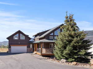 View of front of home with a mountain view, an attached garage, asphalt driveway, and board and batten siding