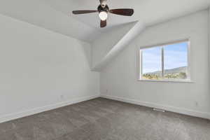Bonus room with a mountain view, carpet flooring, vaulted ceiling, and a ceiling fan
