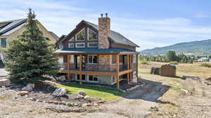 Front view of property and yard, a deck with mountain view, and driveway